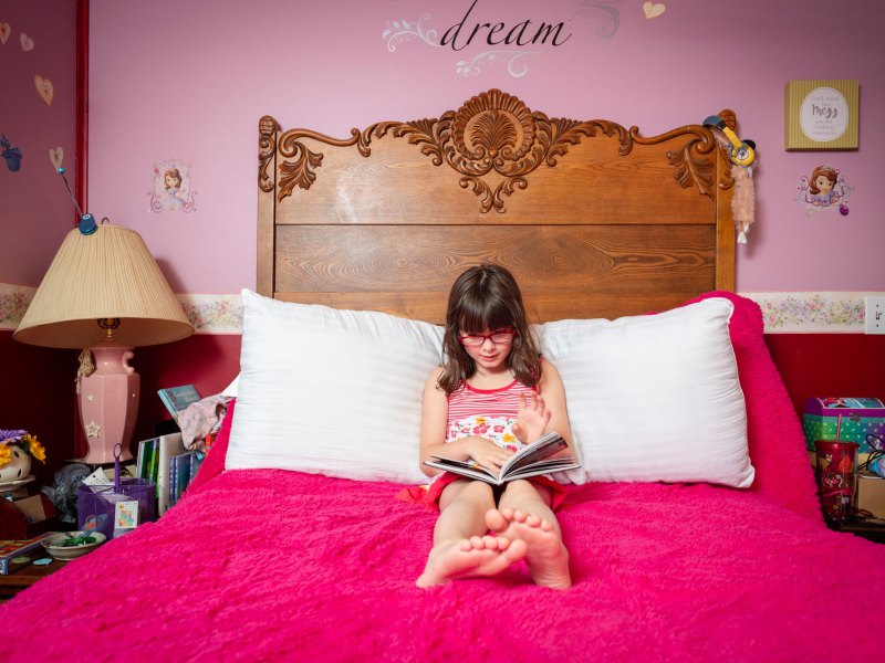 Tessa, 7, of Lafayette, Indiana, reads a book in her bright pink bedroom.