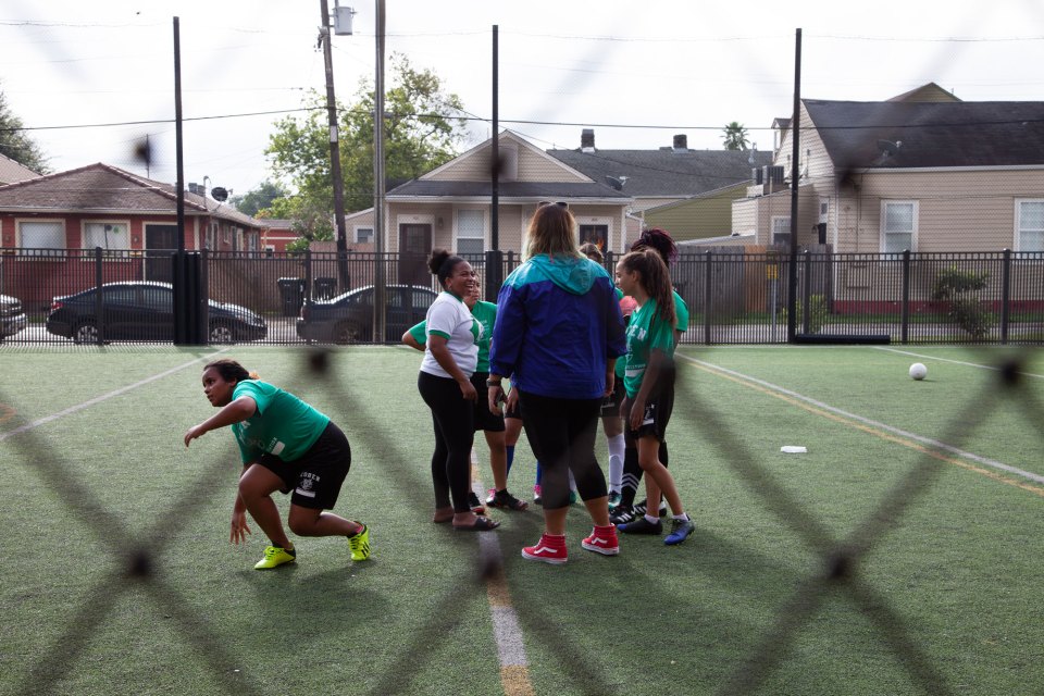 Girls Coach Katie Lucky-Heard (left, white shirt) delivered a half-time pep talk to her team. “Tú puedes,” she said. You can do it.