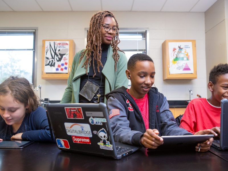 Teacher and three boys working on tablets