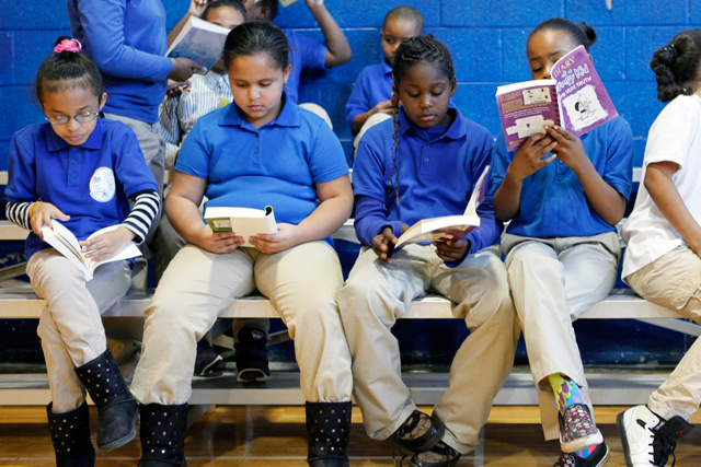 In the Quitman gym, students look at the new books they received as a reward for the school’s academic progress. (Amanda Brown / NJ Spotlight)